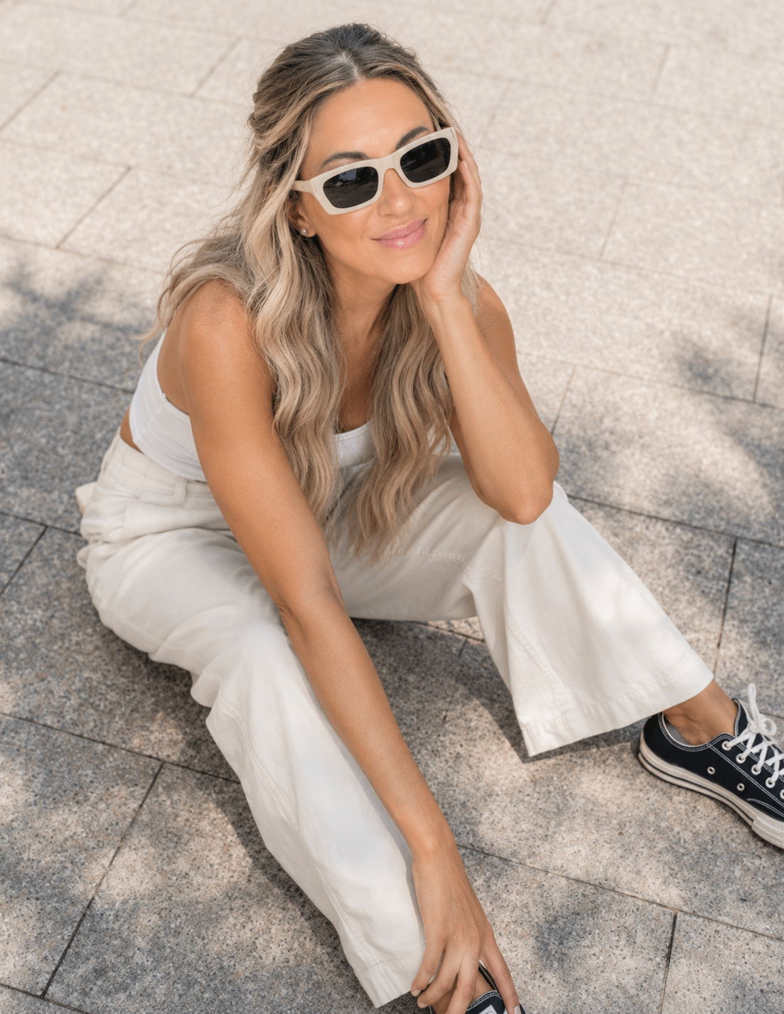 Bridget Wallace sitting outside in a white outfit, smiling up at the camera